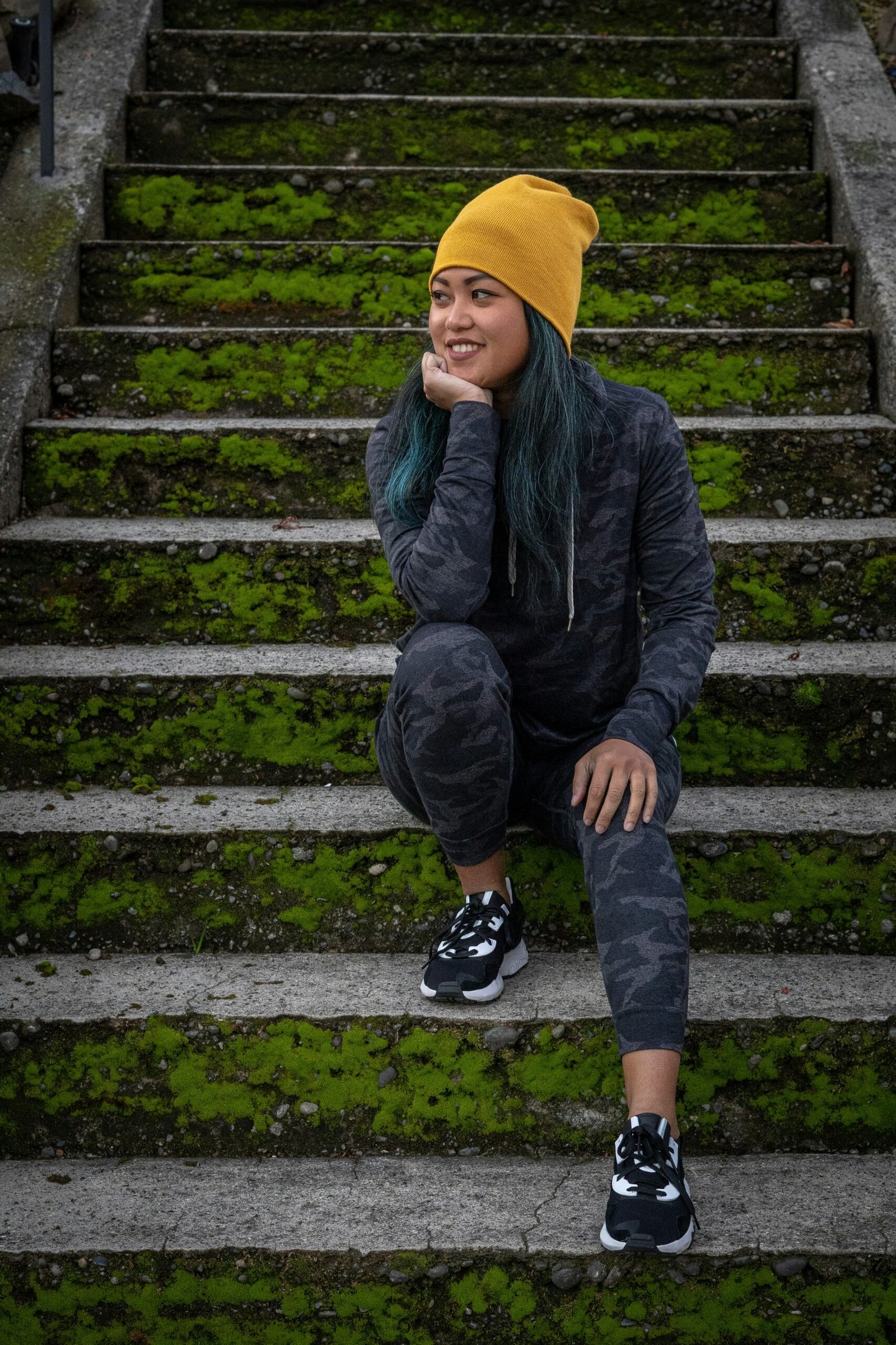 boy in black jacket and yellow knit cap sitting on concrete stairs